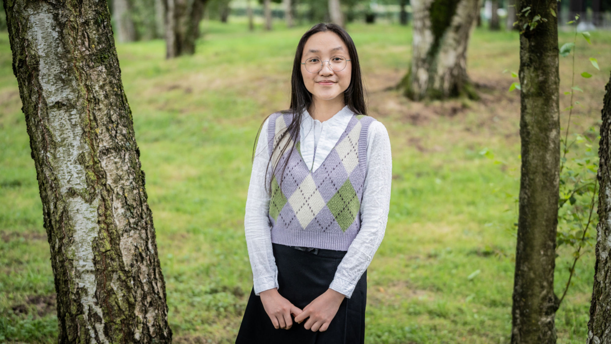 Hanh Nhi steht zwischen Bäumen im Campuspark