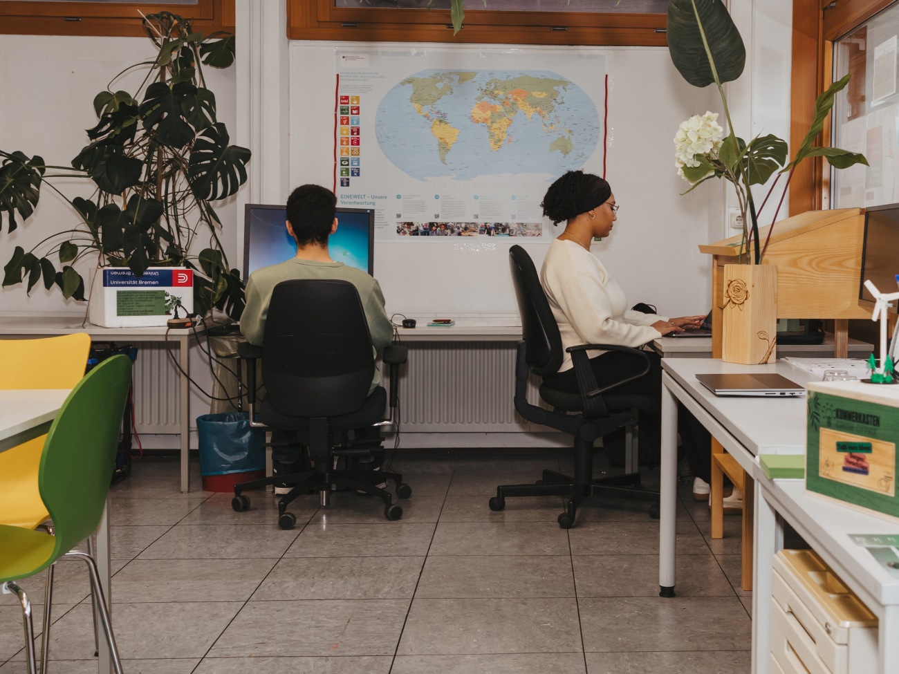 Two people are sitting at desks in an office.