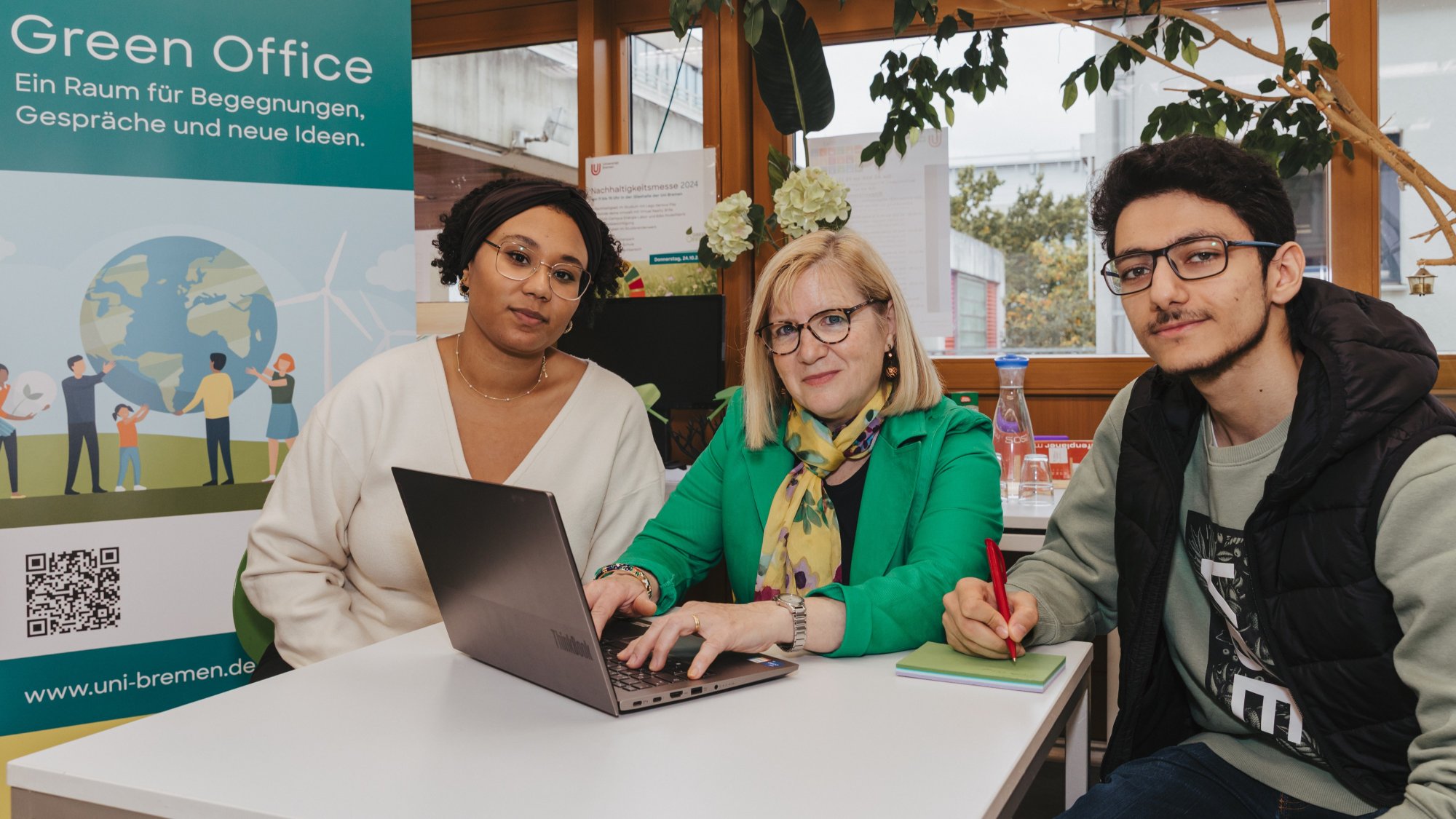 Three people are sitting at a table with a laptop in front of them.