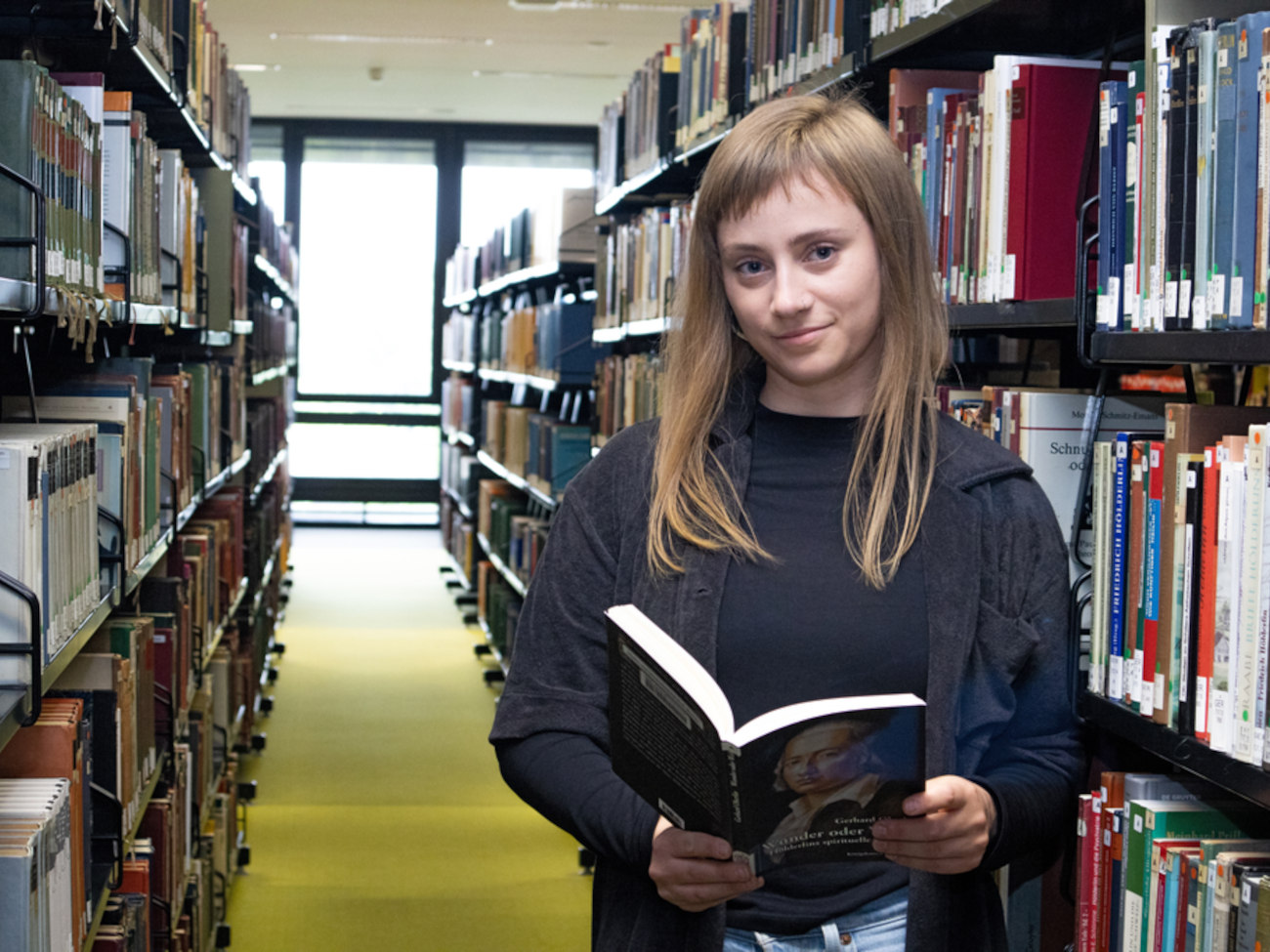 Jenny mit einem Buch in der Bibliothek