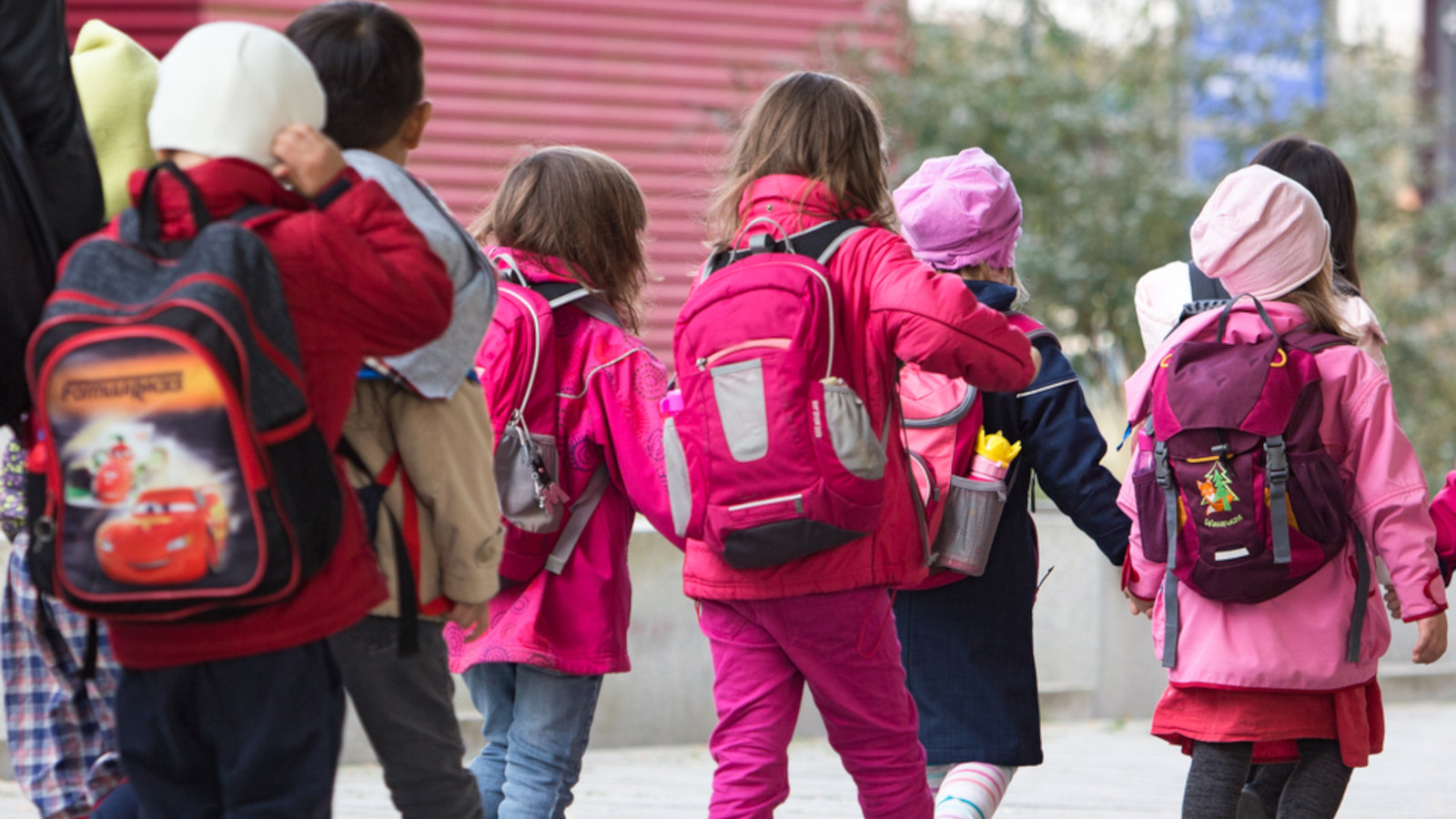 Kinder mit Rucksäcken laufen über den Campus