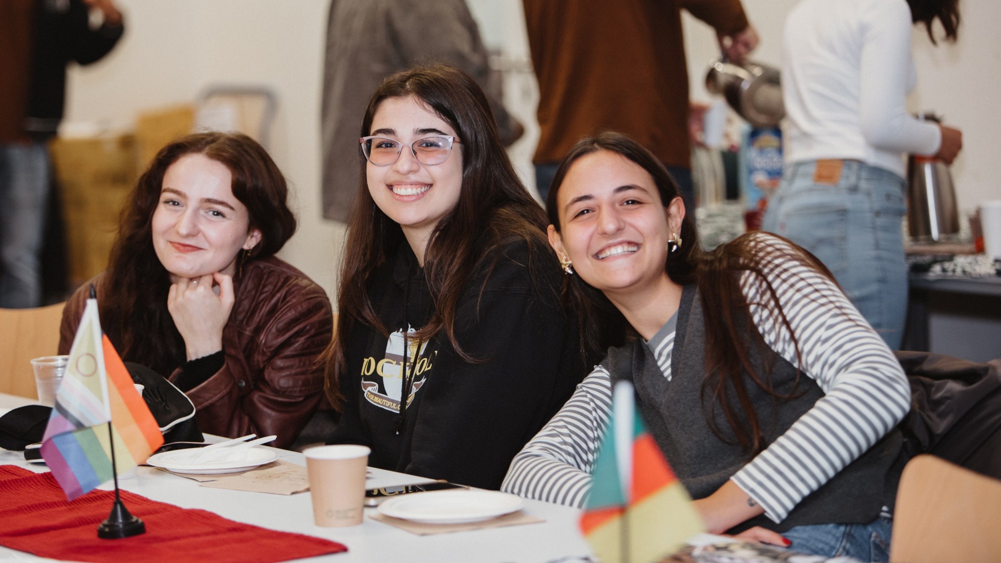 Three people are sitting at a table and are smiling at the camera.