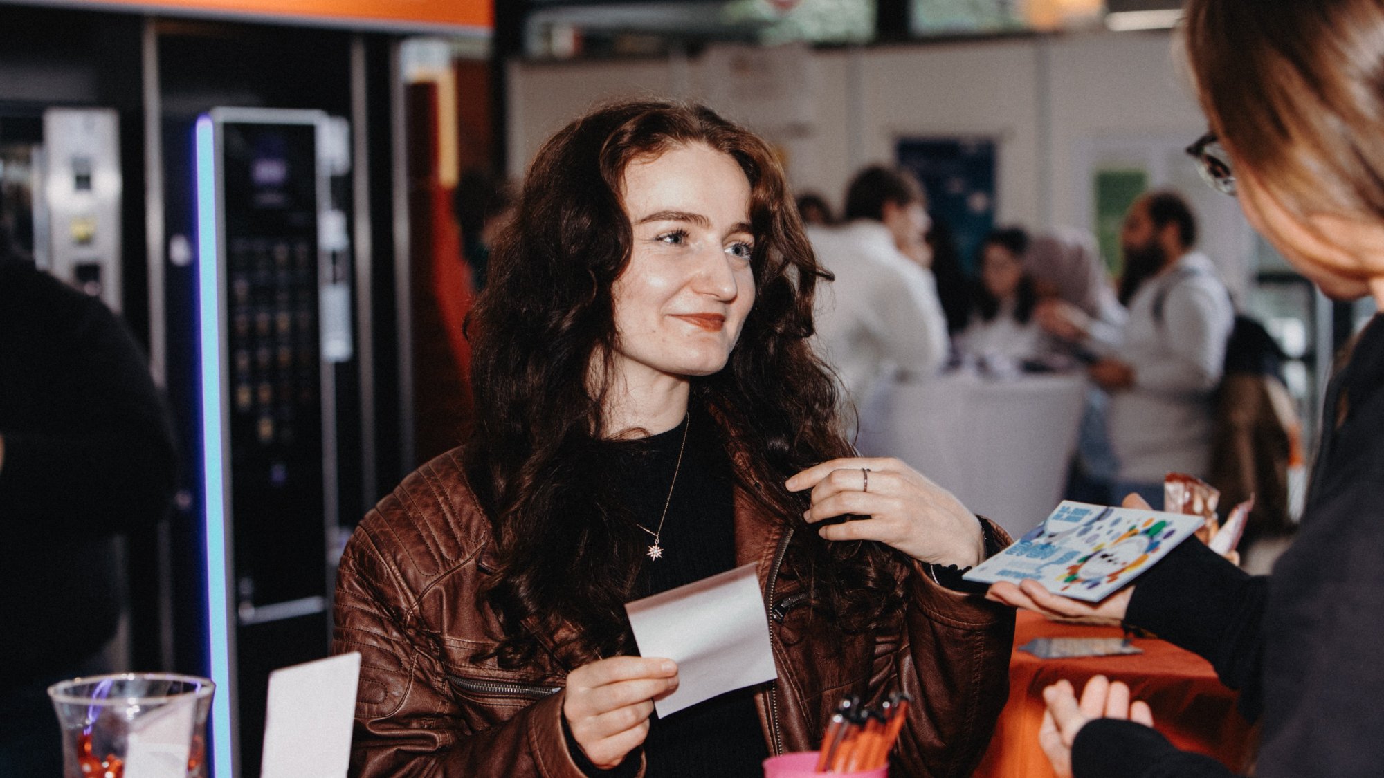 A person is handed a flyer at an information stand. 