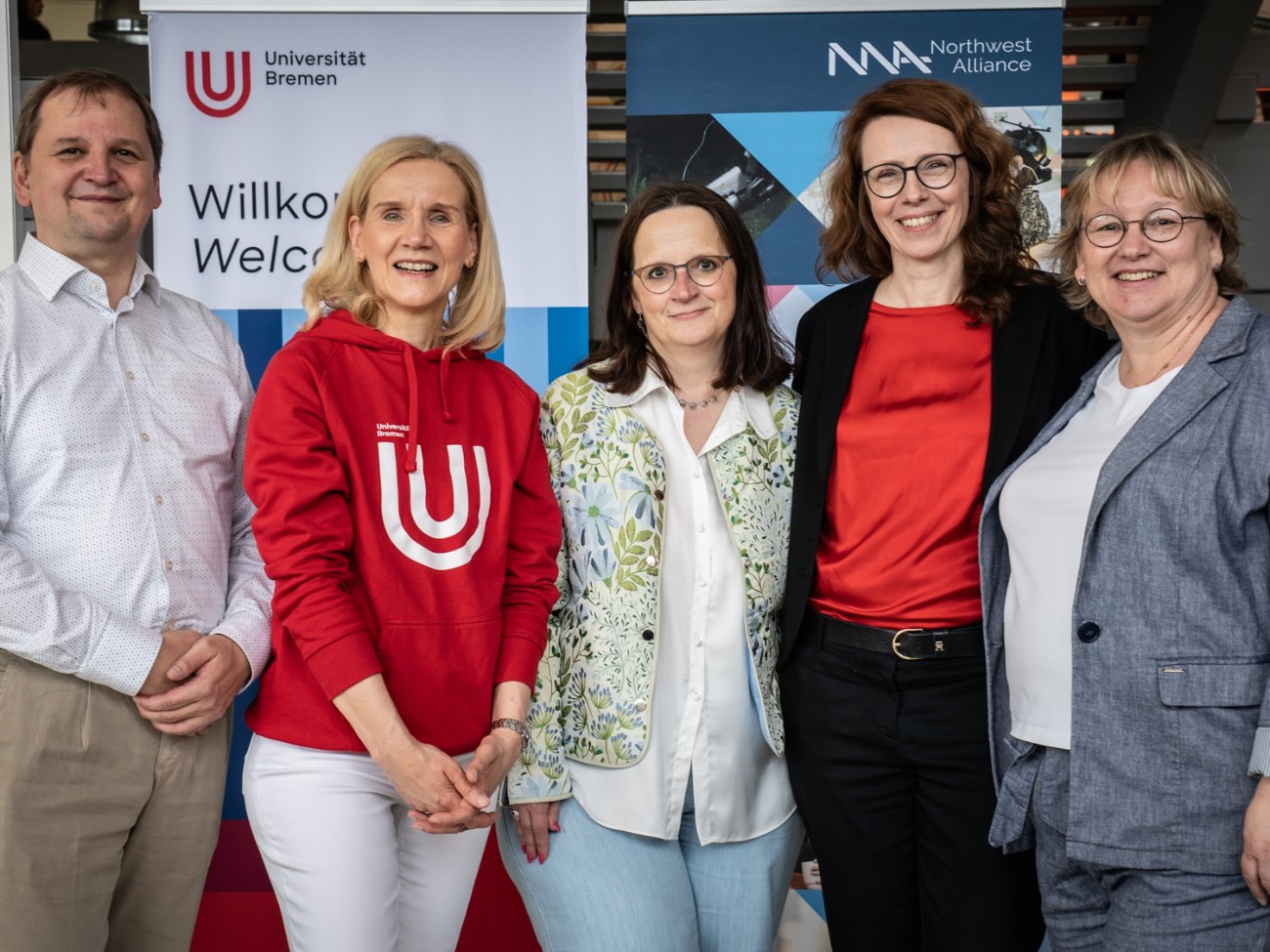 The University of Bremen’s Executive Board and the Northwest Alliance (5 people) are standing in front of a University of Bremen and NWA banner and smiling at the camera