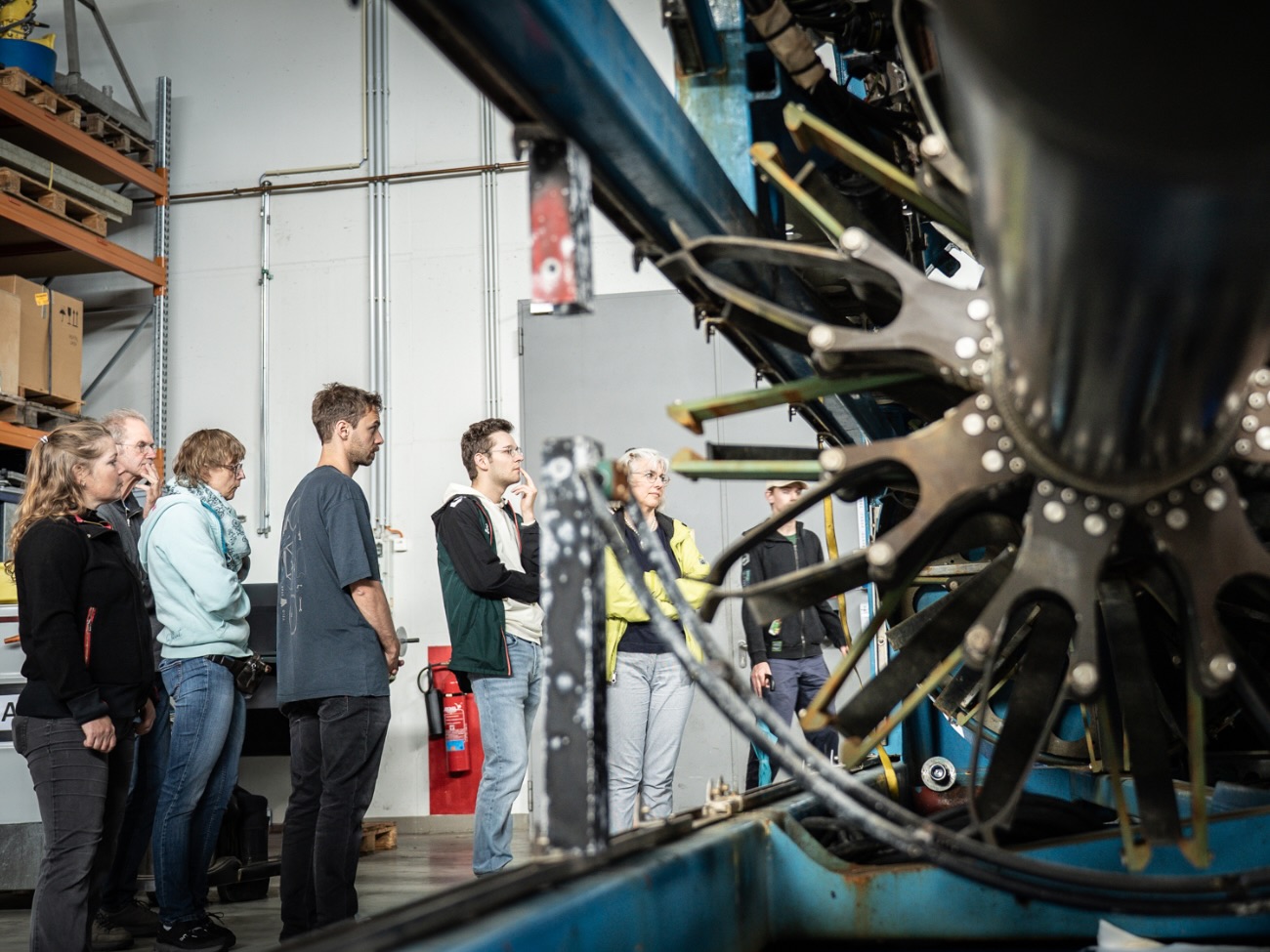 A group of people is inspecting a large, complex machine.  