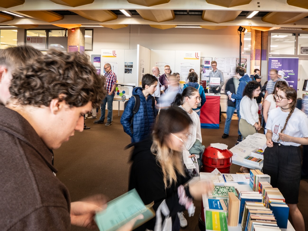 People are standing at information booths and reading brochures. 