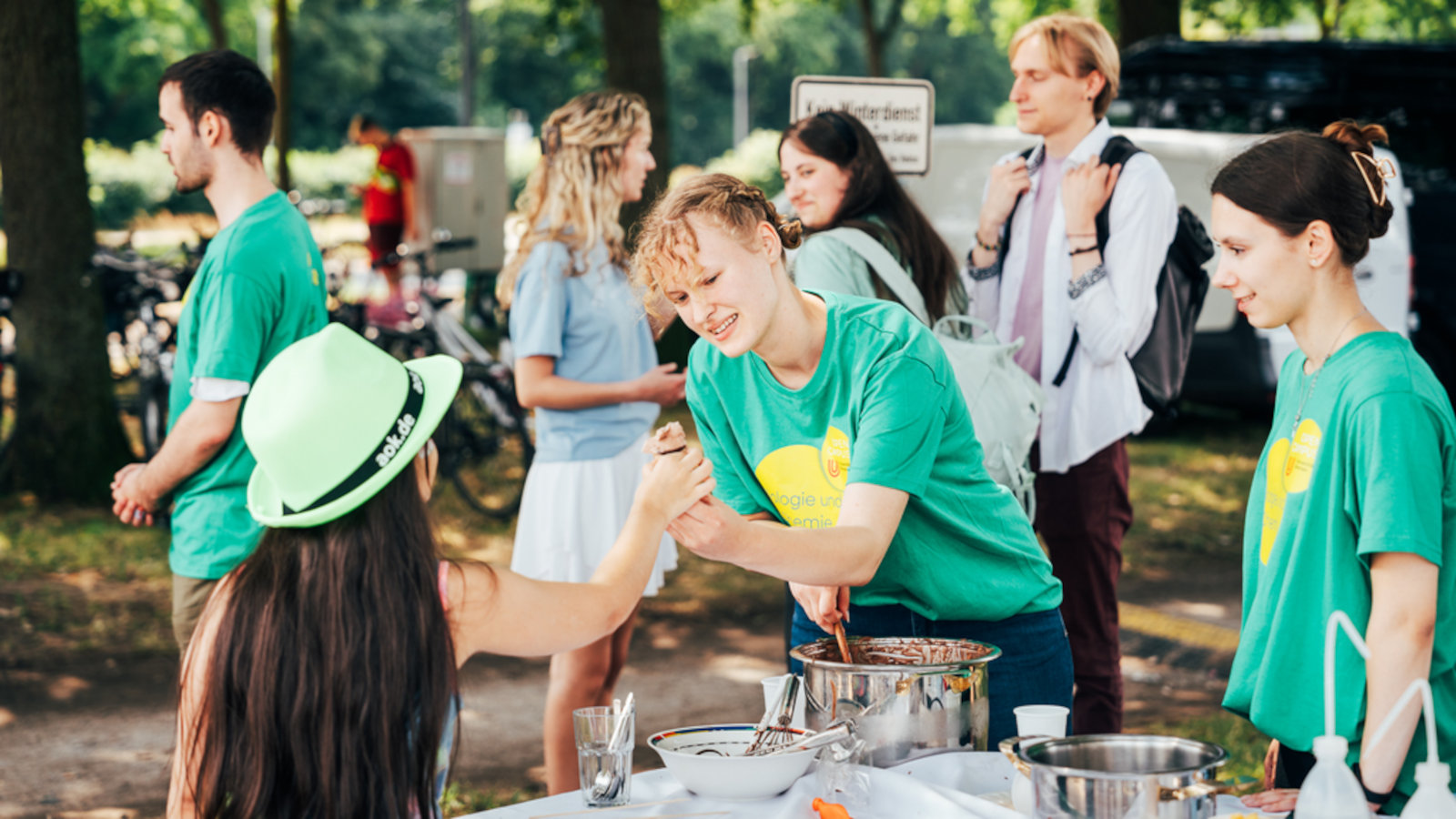 A person of the Faculty of Biology and Chemistry hands an ice cream to a girl.