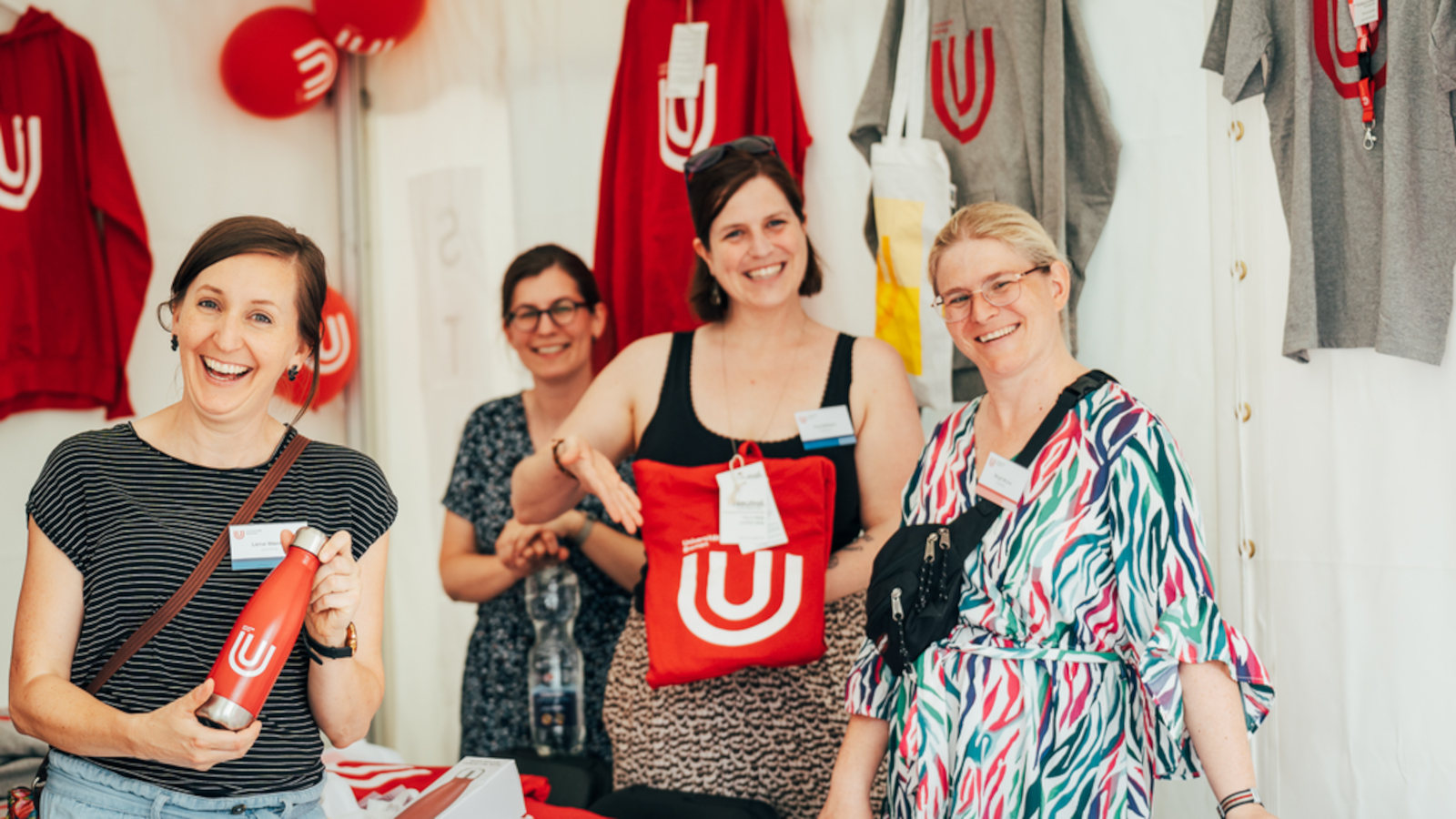 Mitglieder des Team des Referats für Hochschulkommunikation und -marketing (KOMMA) halten Merch der Uni Bremen