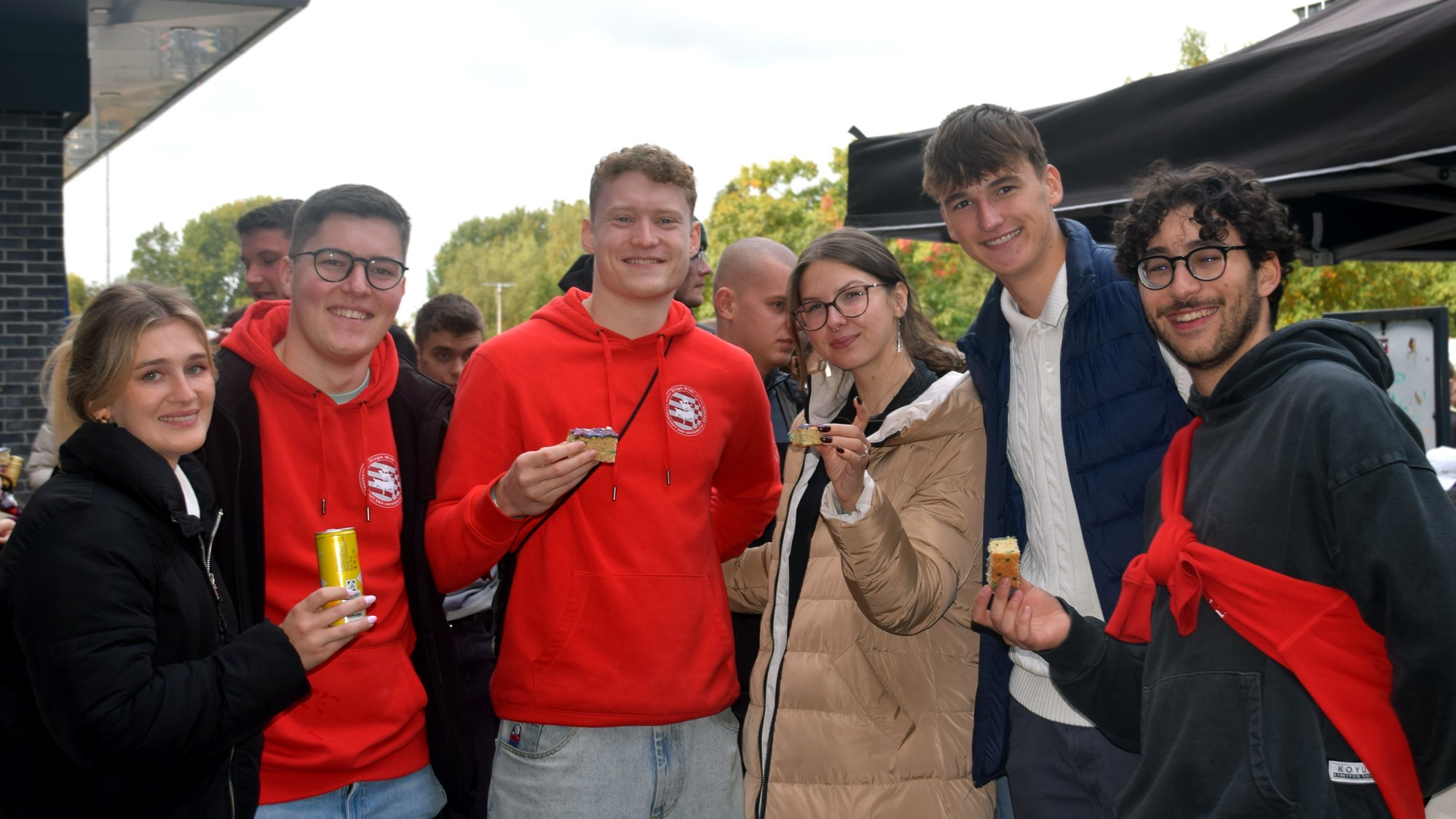 A group of six people are standing together and are smiling at the camera.