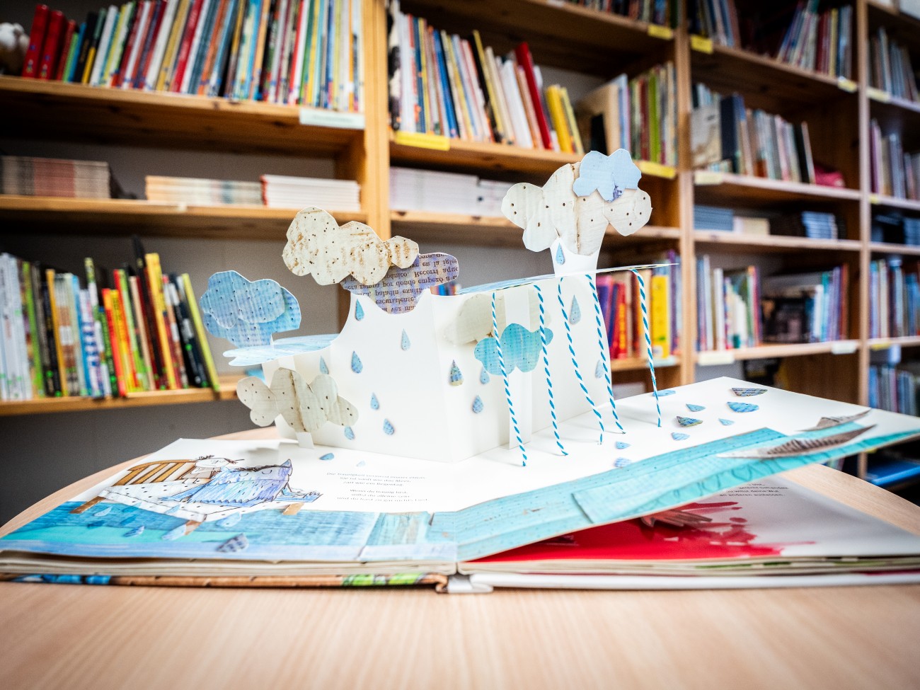 Ein aufgeschlagenes Bilderbuch, auf dessen Seite ein 3D-Modell aus Papier aufgeklappt ist.
