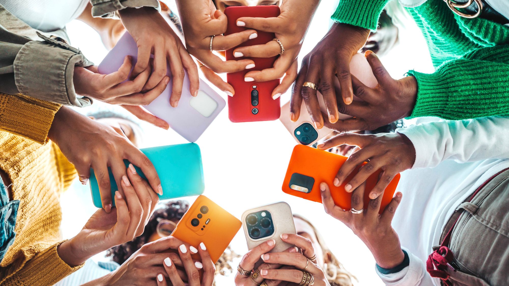 People with smartphones in colorful cases are standing in a circle.
