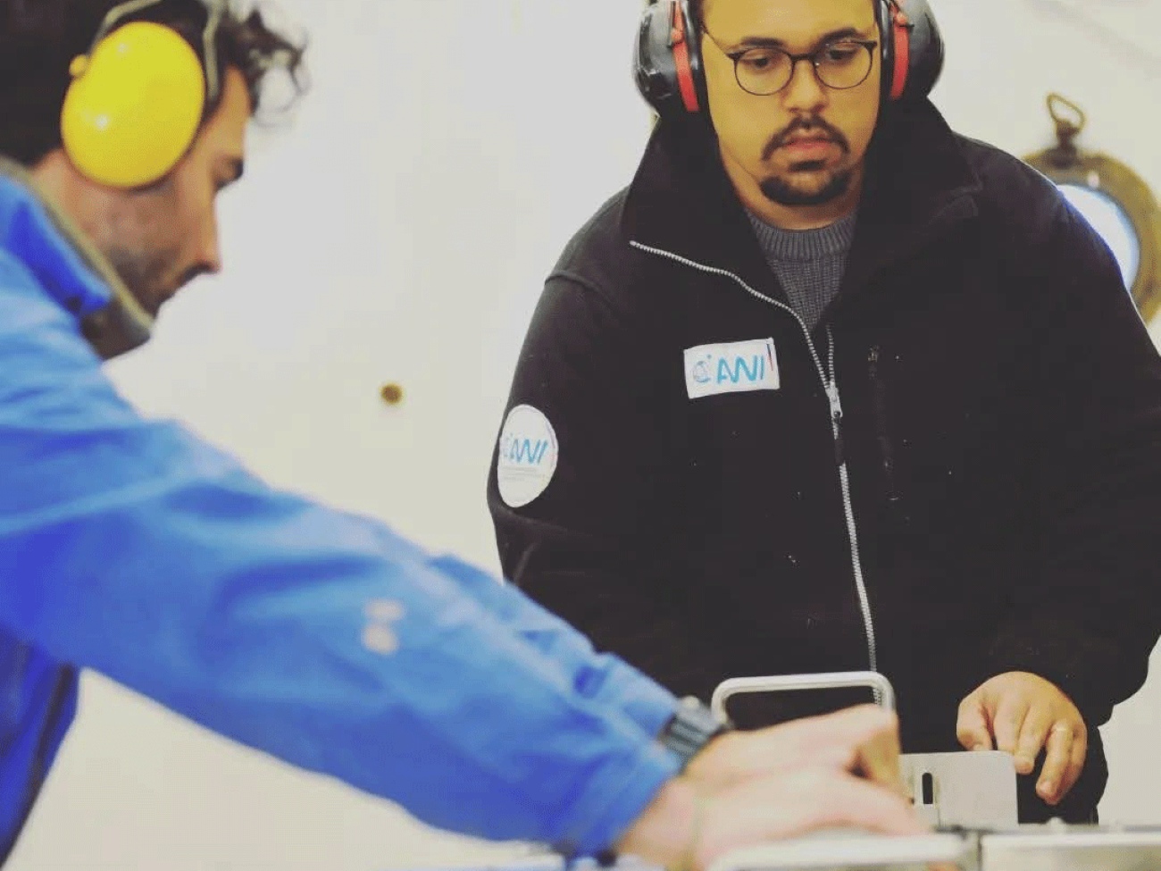 Two men wearing ear protection are working on a table.