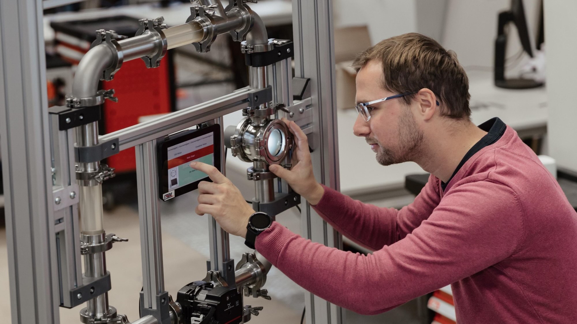 A person is handling a pipe structure equipped with a small screen. 