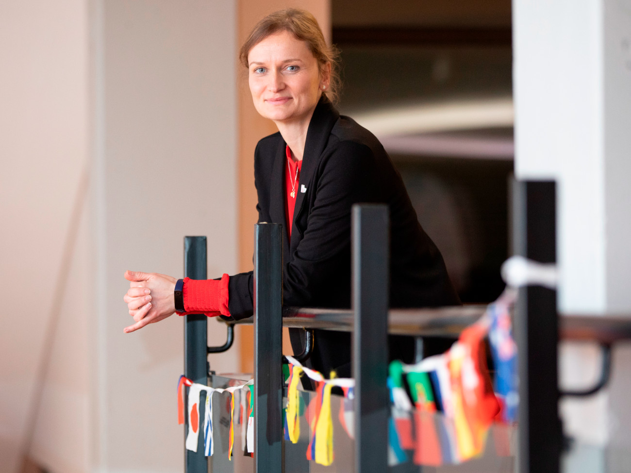 Julia Holz lehnt an einem Geländer, an dem verschiedene Nationalflaggen angebracht sind.