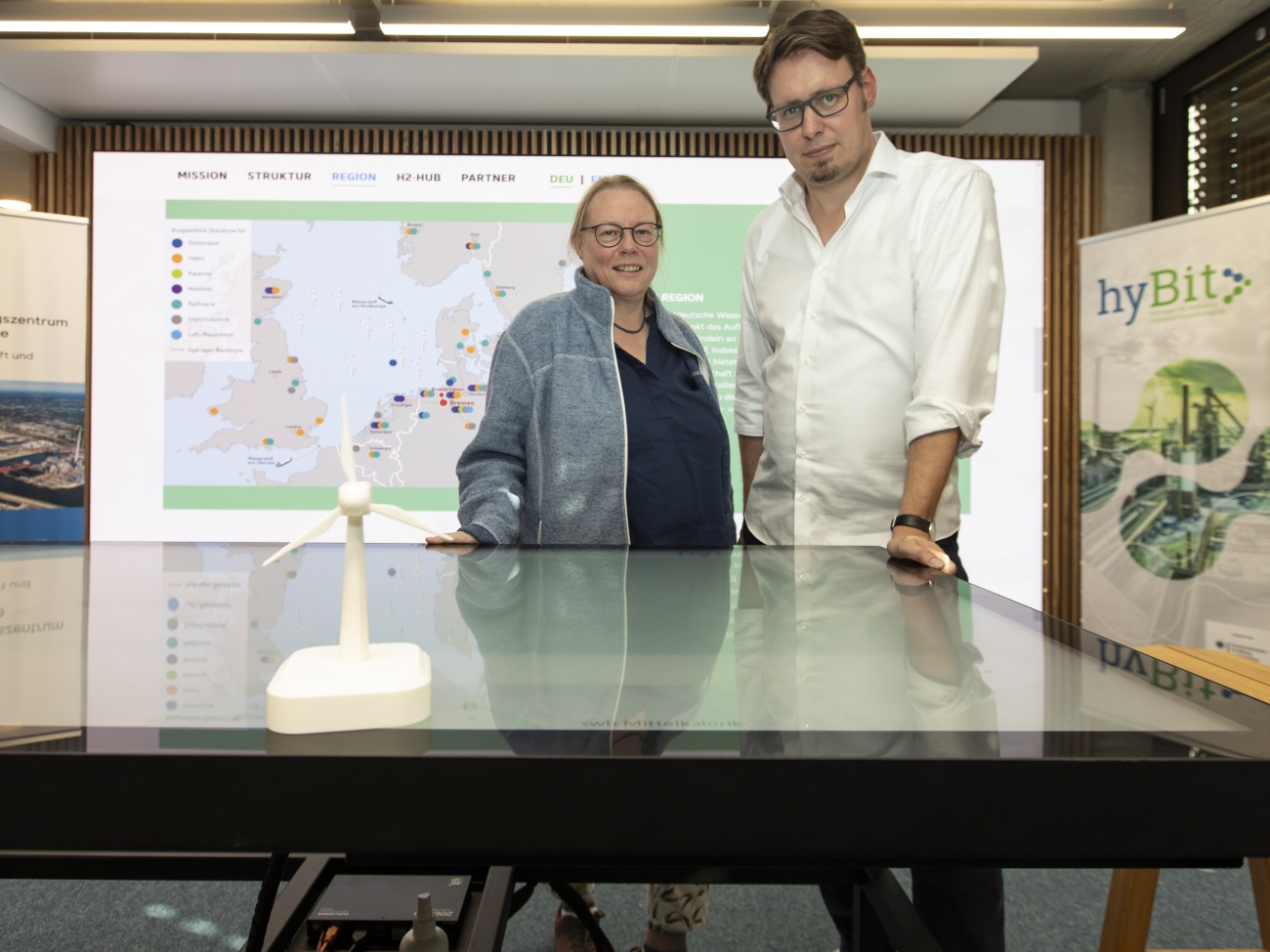 Die zwei Professoren stehen hinter einem Tisch im virtuellen Transformationslabor.