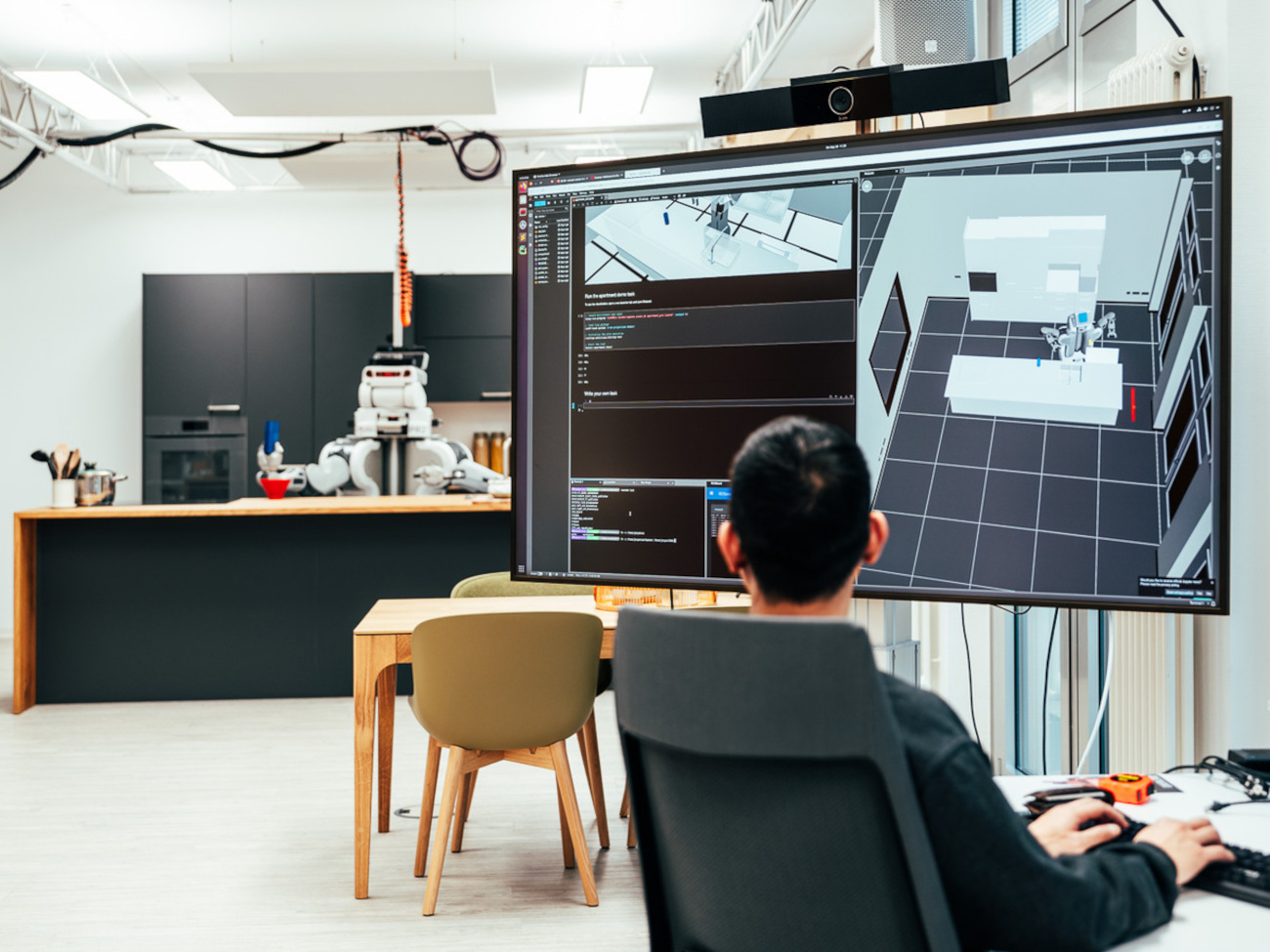 A person sits in front of a screen and experiments with the digital robots