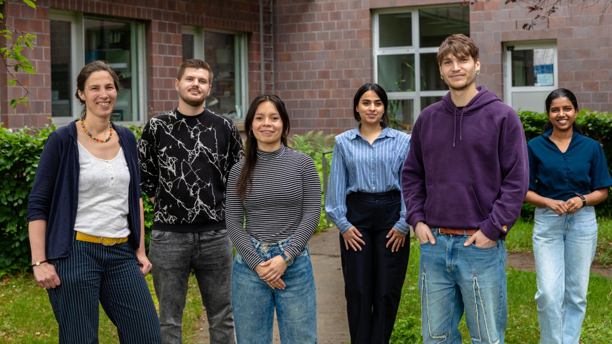 Several people are standing in a row and smiling at the camera for a group photo.
