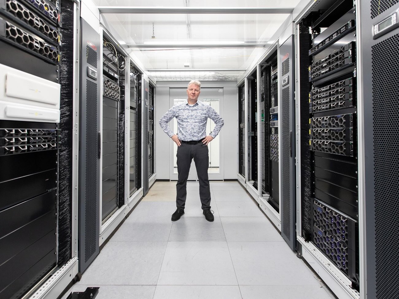 Matthias Werner stands in the middle of a data center in a power pose.
