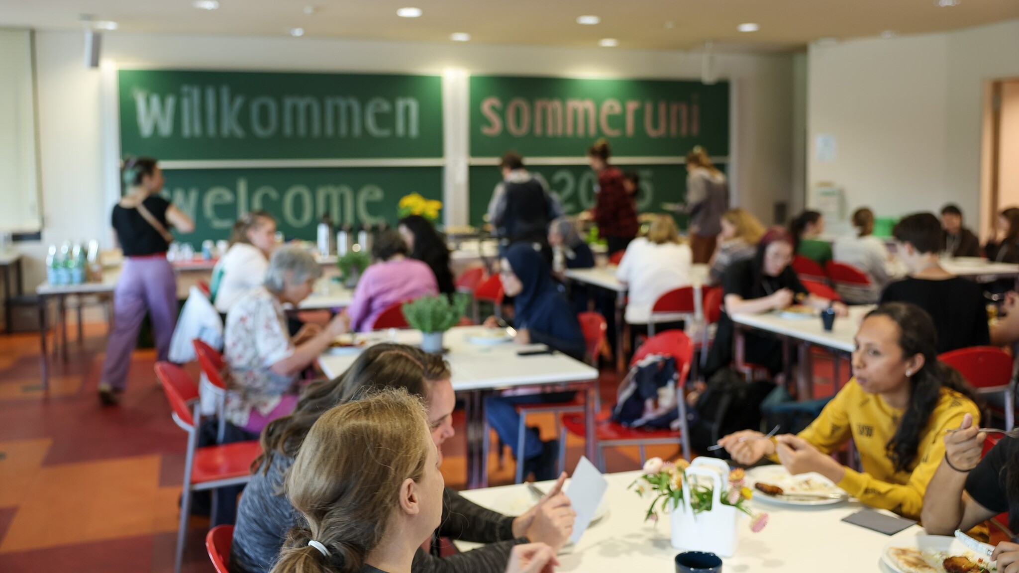 Frauen sitzen an Tischen und essen gemeinsam