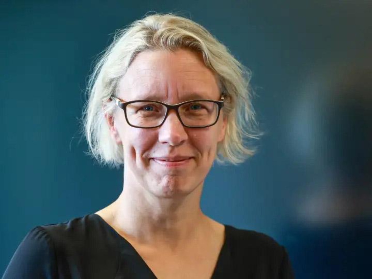 Ein Portraitfoto von Kerstin Radde-Antweiler vor einem dunkelblauen Hintergrund.