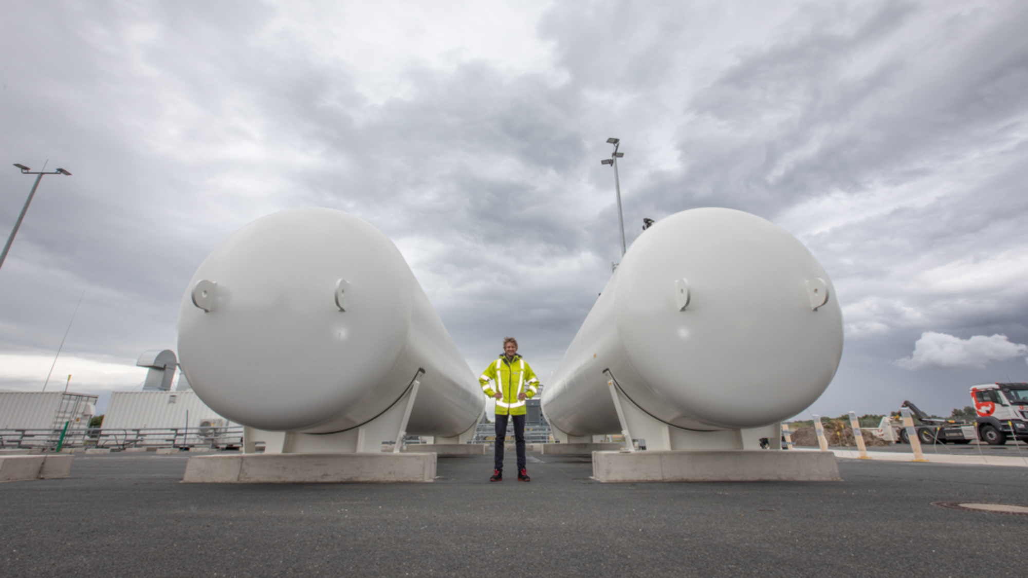Jannes Vervoort is standing between two elongated tanks, in which green hydrogen is stored