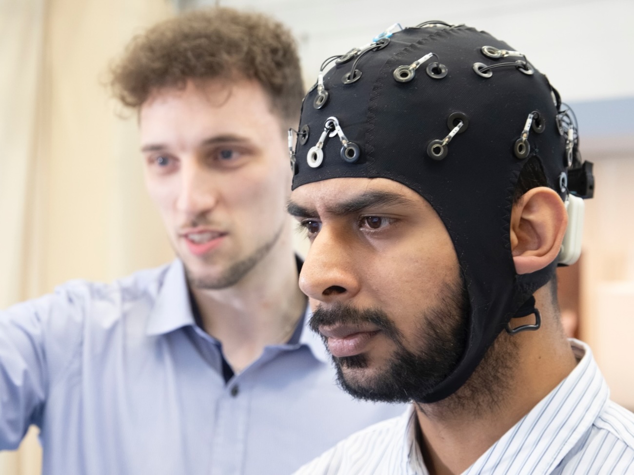 A portrait photo of Saurav Pahuja and Dr. Marvin Bursdorf. Both are looking in the same direction, and Saurav Pahuja is wearing a wired cap. 