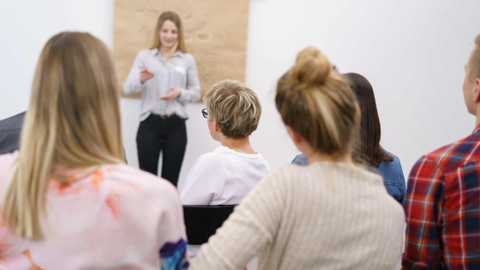 Audience of a meeting looks at a woman