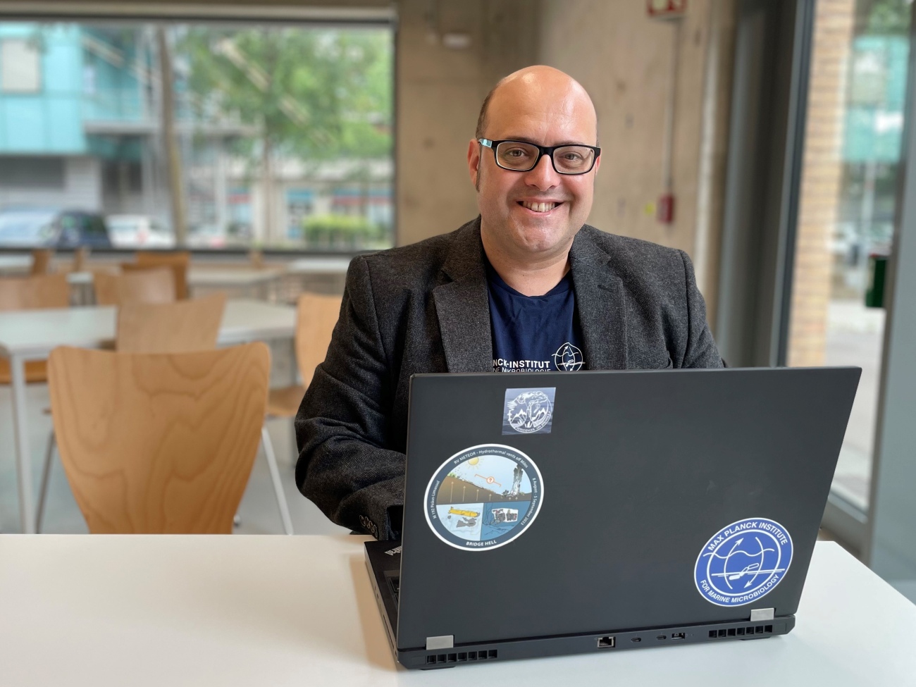 A person is sitting at a table and smiling at the camera.