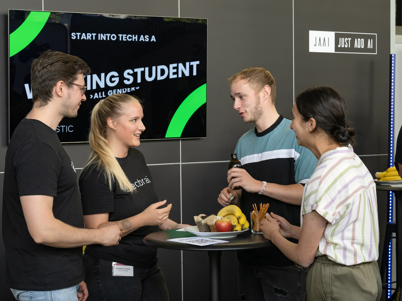 Four people stand at a booth at the job fair and talk.