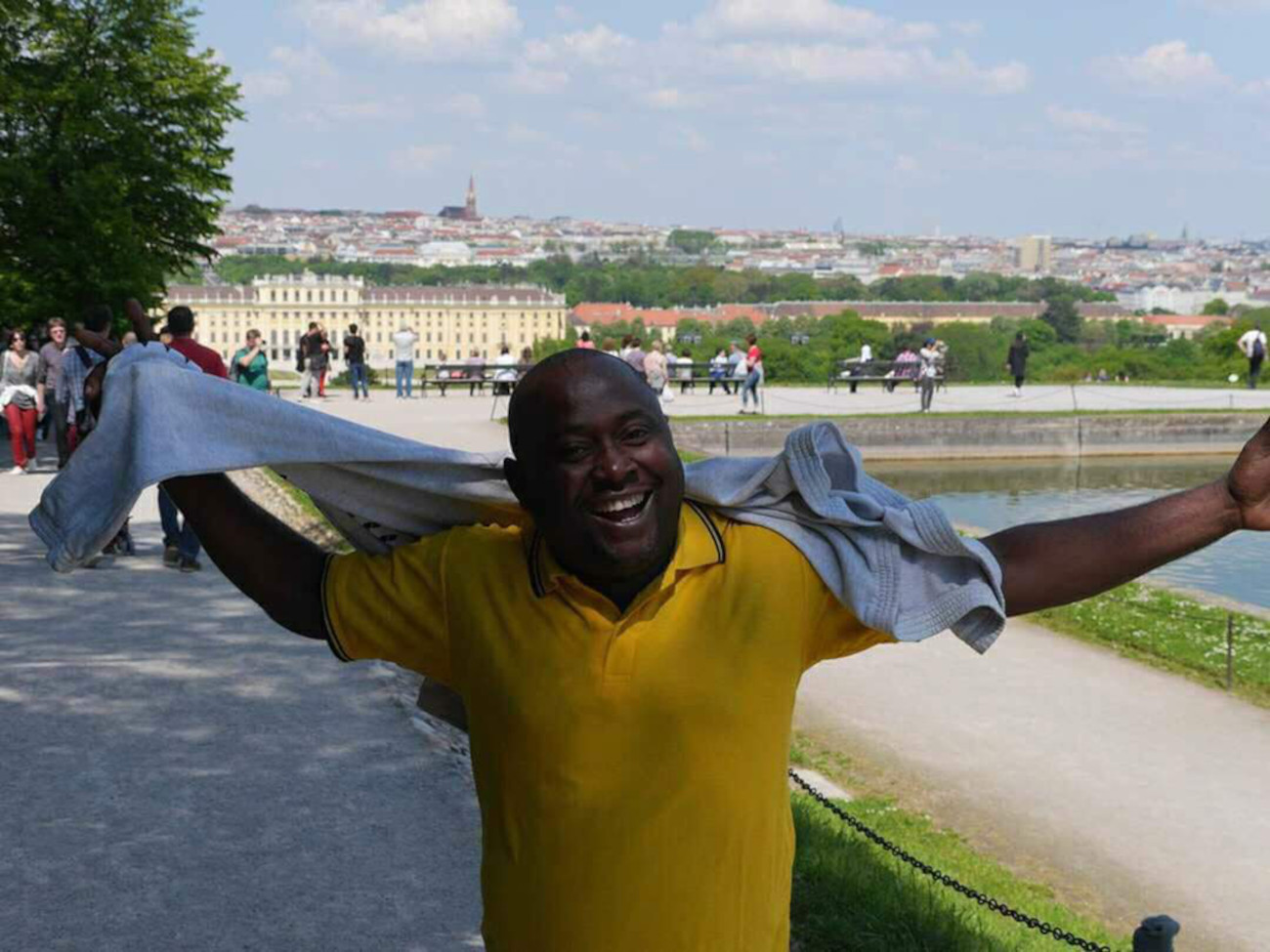 The artist Recaredo Silebo Boturu laughs into the camera. A city can be seen behind him.