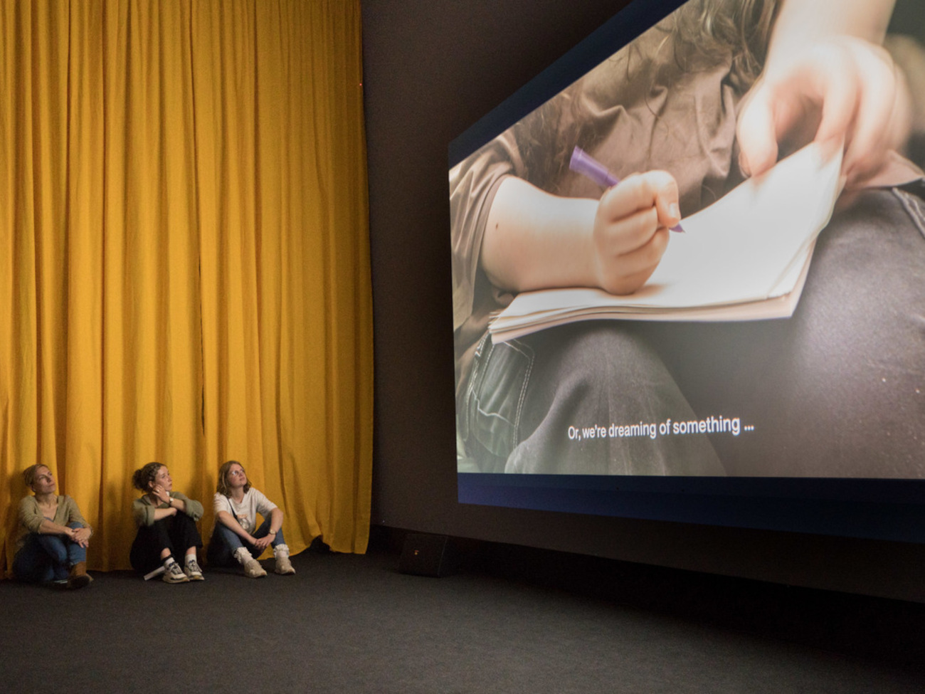 A group of young people watches with interest a talk at the “Youth vs. Crisis: A Generation in Search of a Future” exhibition. 