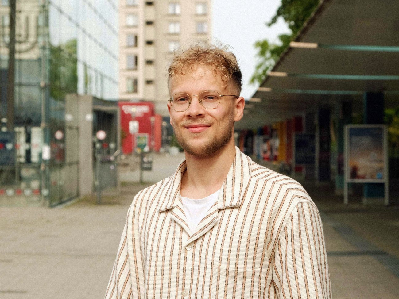 Ein Mann steht auf dem Boulevard und lächelt in die Kamera.