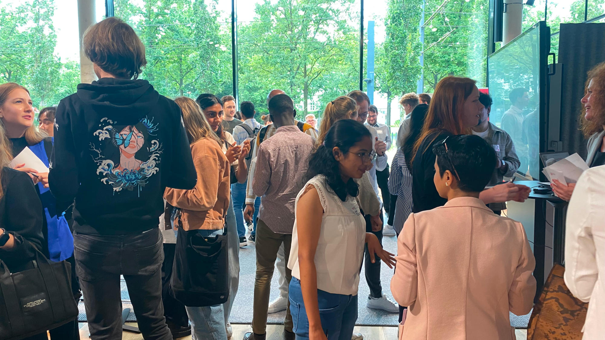 Students chat at the summer camp, green trees can be seen through the windows in the background