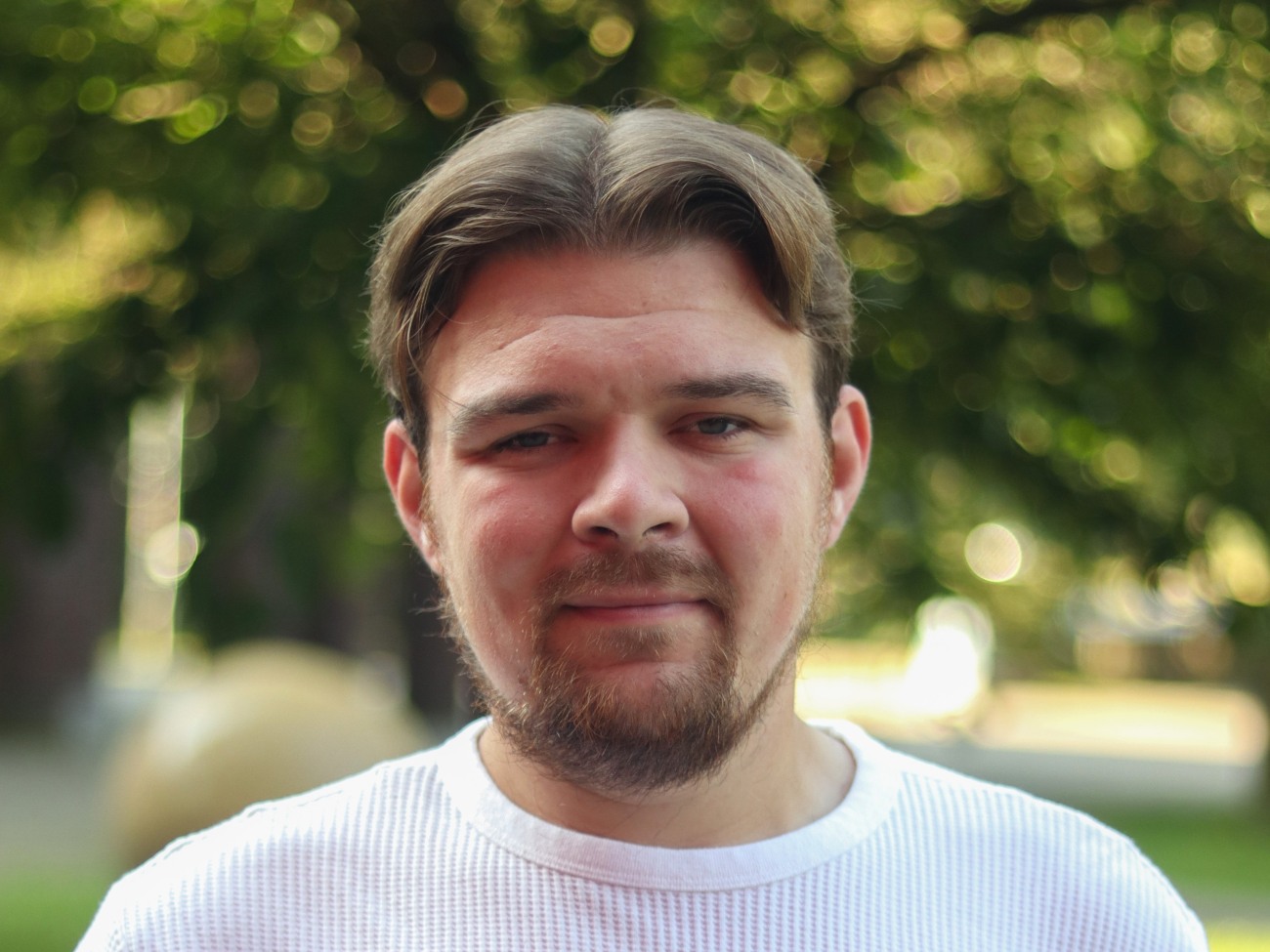 Porträt von einem Mann, der in die Kamera lächelt.