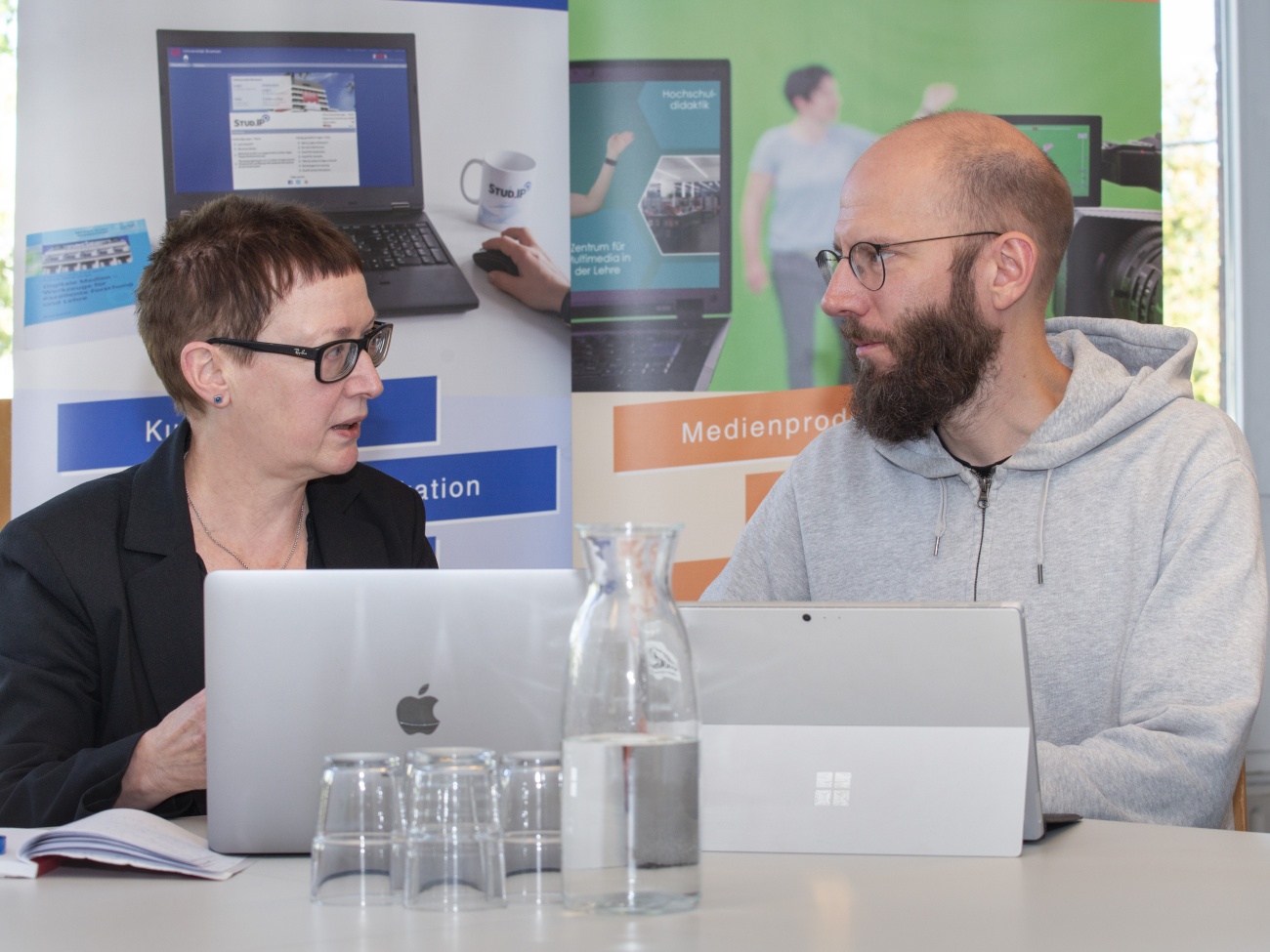 Zwei Personen sitzen an einem Tisch und sprechen miteinander.