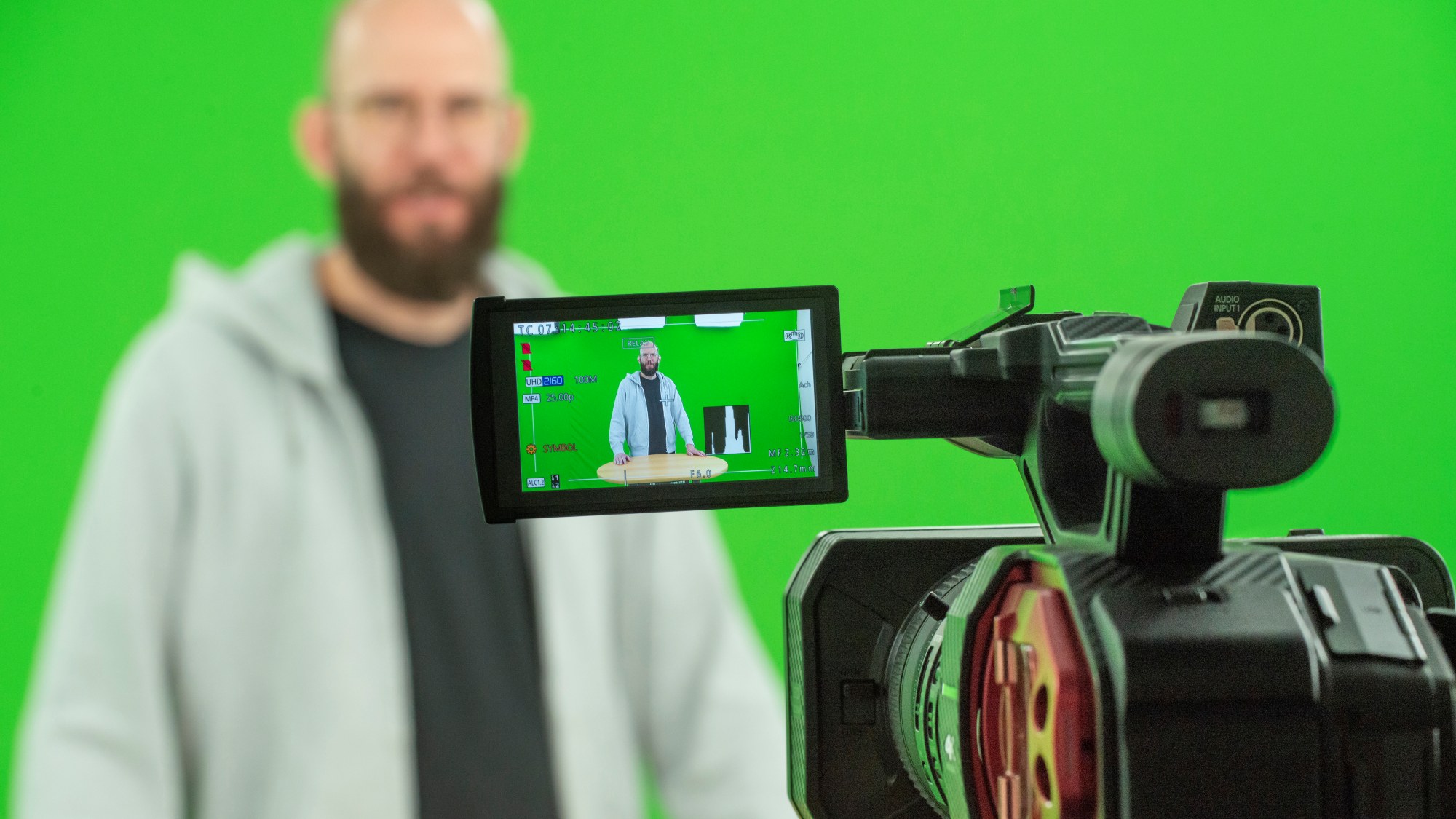 Ein Mann blickt in eine Videokamera, welche auf dem Bild zu sehen ist.