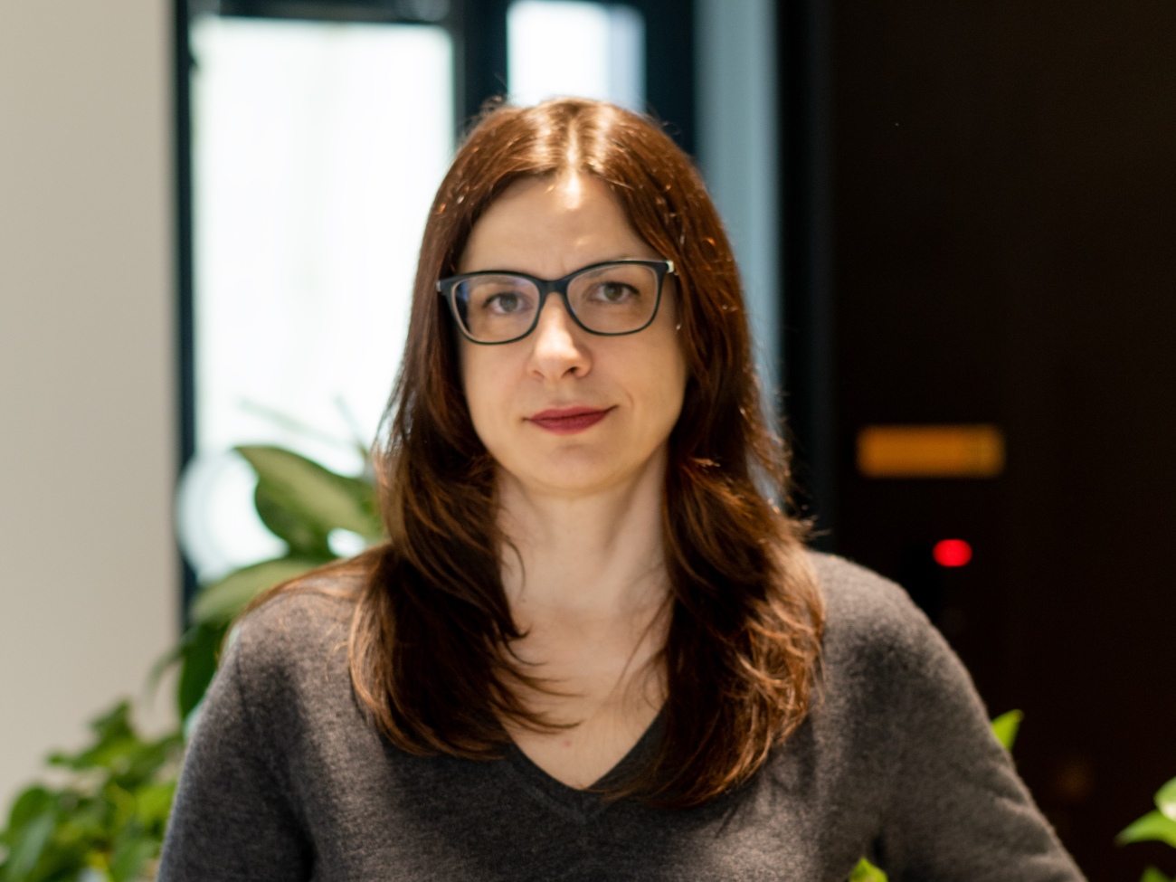 Ein Porträt einer Frau mit Brille, die in die Kamera blickt.