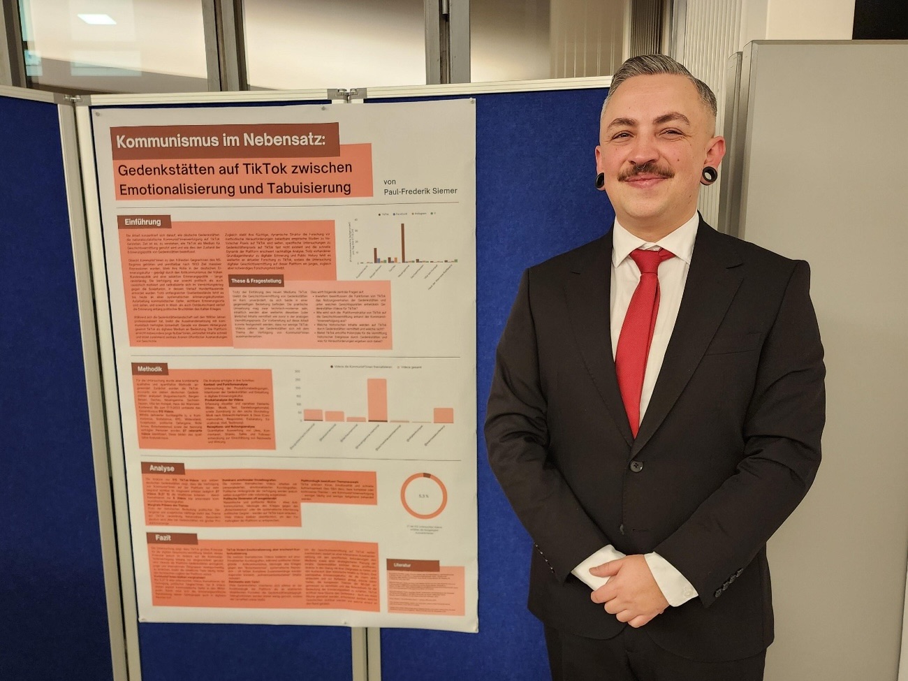 Mr. Siemer stands smiling next to a blackboard displaying contents of his master's thesis.