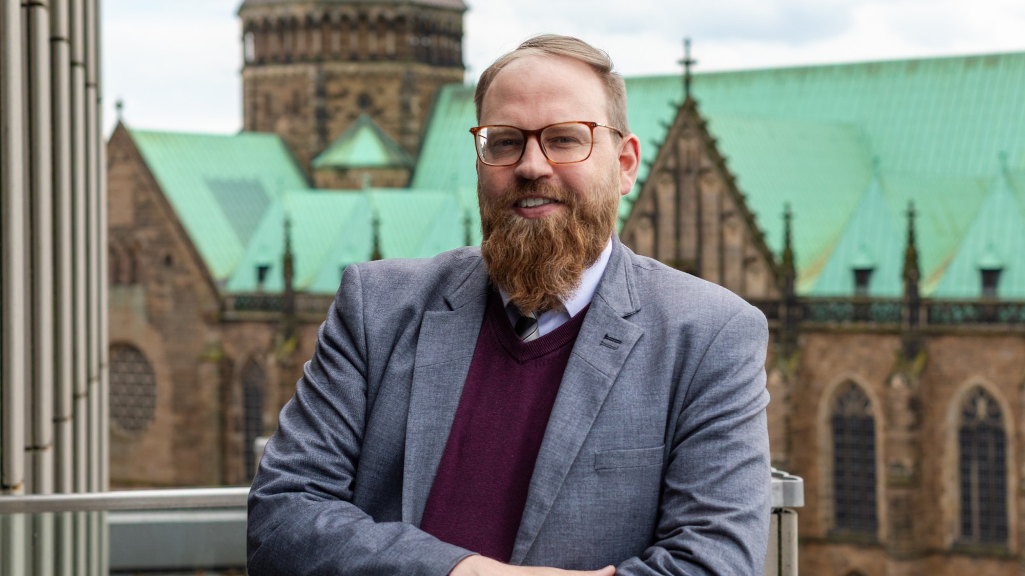A person smiles at the camera. The Bremen Cathedral can be seen in the background.