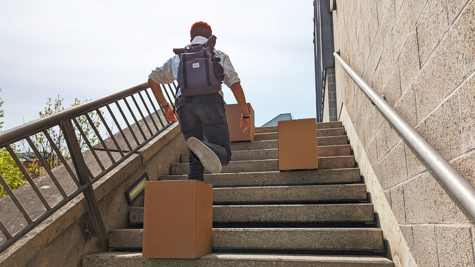 Young man with backpack is walking up stairs avoiding obstacles.